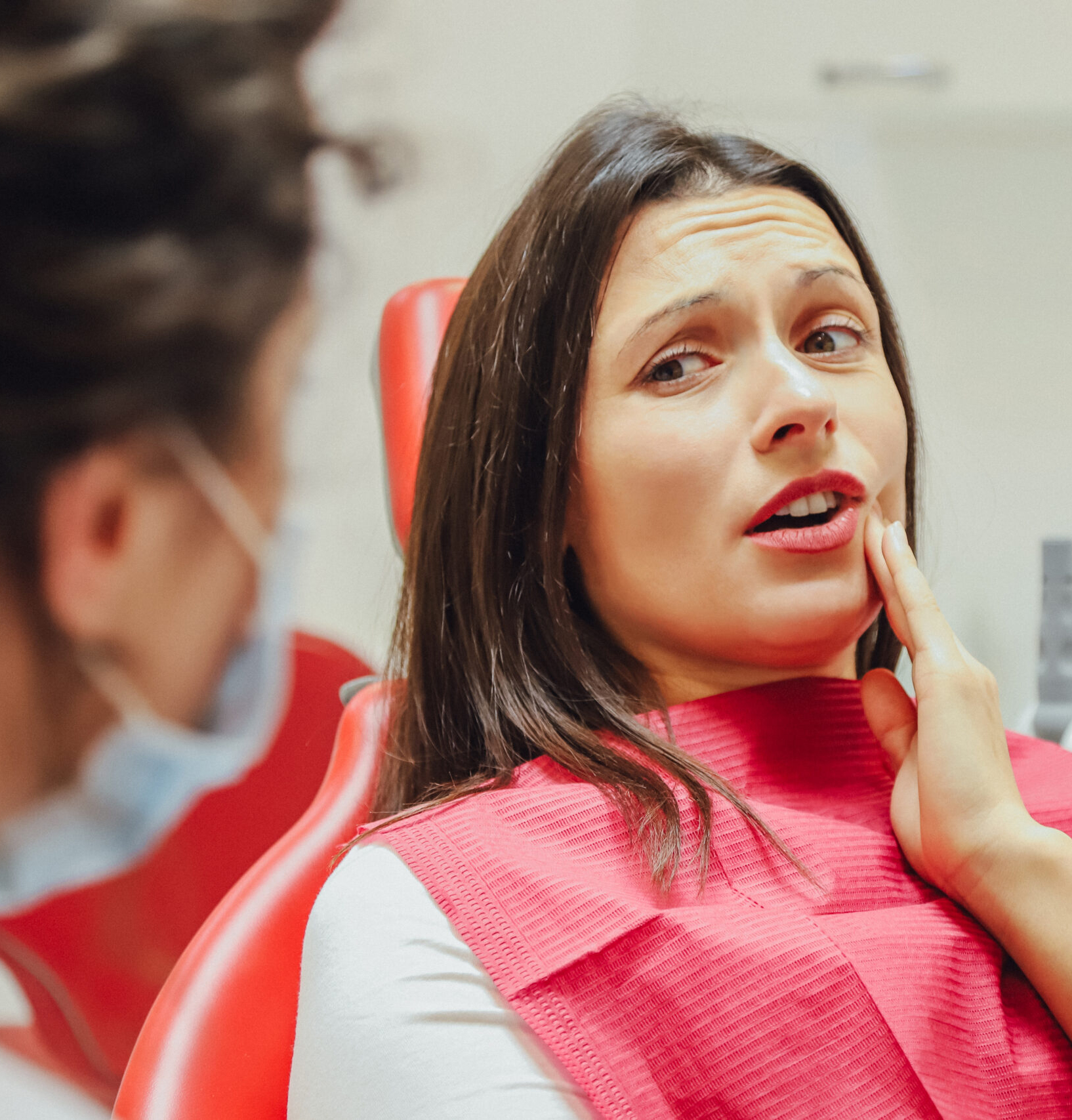 Close-up portrait of a sad young girl with a painful tooth, a doctor in office chairs, an isolated dentist office background clinic. Close-up portrait of a sad young girl with a painful tooth, a doctor in office chairs, an isolated dentist office background clinic. Expressions of the human face, emotions, feelings, reactions